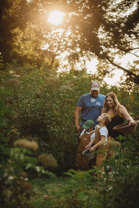 Us at our organic elderberry farm outside of Columbus Ohio. We (Lisa and John) are smiling at our two sons, Easton and Nixon, as we all pick elderberries together. Our boys are always helping us make the best elderberry syrup recipe for our amazing customers.