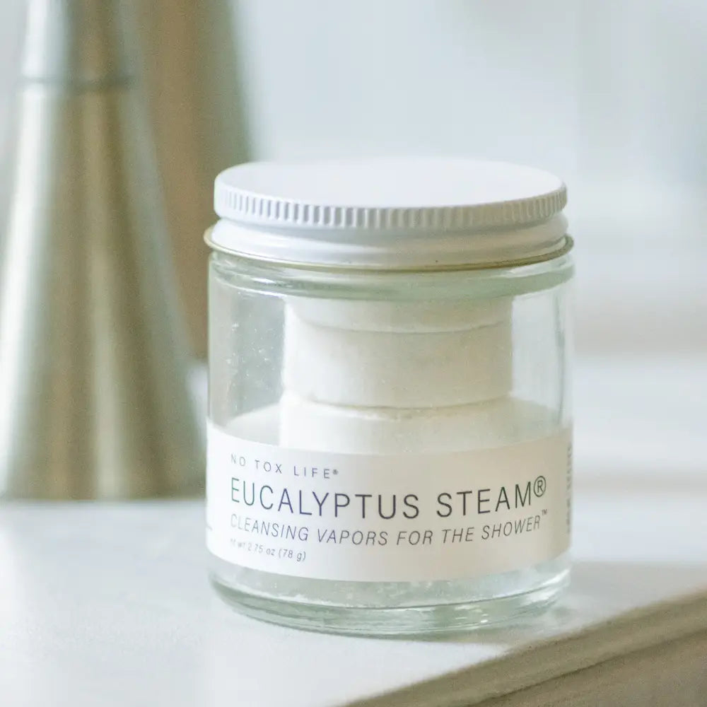 Jar of Eucalyptus Steam product on a surface with a blurred background