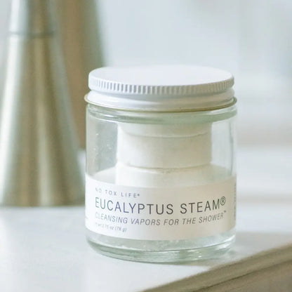 Jar of Eucalyptus Steam product on a surface with a blurred background