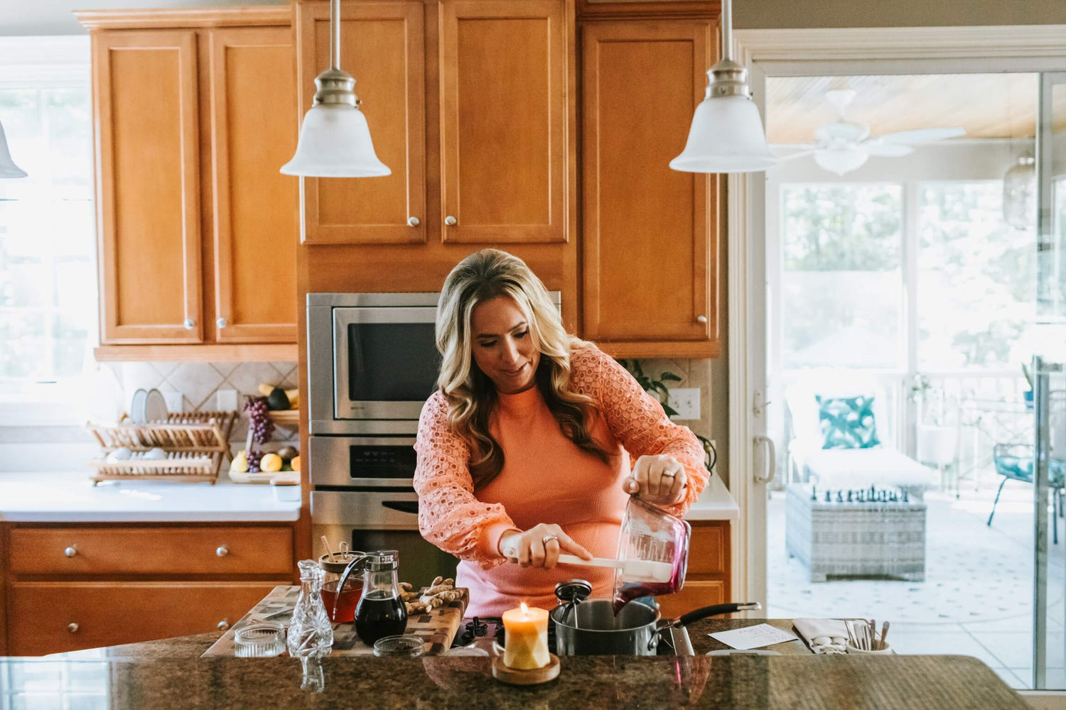 Lisa K. in a peach-colored blouse in her kitchen making Above and Beyond Shop's organic fresh elderberry syrup recipe