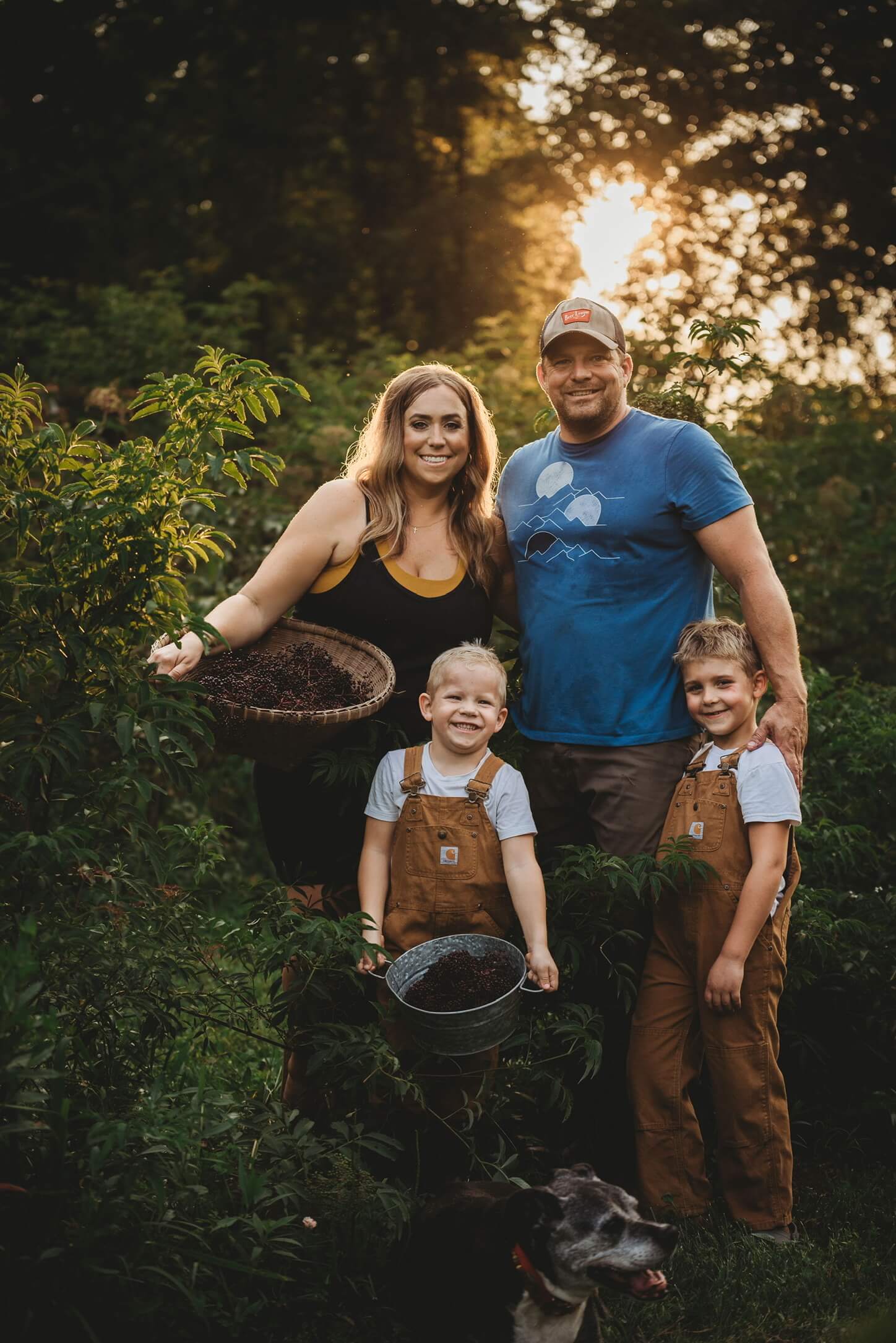 All four of us (Lisa, John, Easton and Nixon) posing for the camera at our organic elderberry farm while holding baskets of hand-picked elderberries (to make the best elderberry syrup and tea).