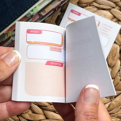 Small, sticky notepad with labeled pages held by a hand on a woven surface